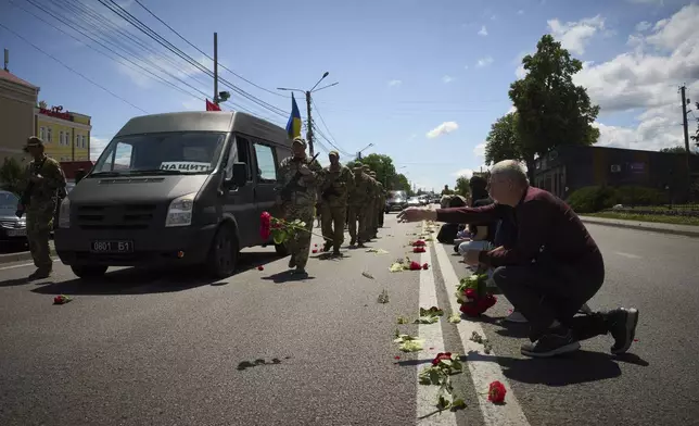 Villagers throw flowers on the road during the funeral procession of Maksym Baluyev, a soldier who was killed in battle with the Russian troops, in the village of Novi Petrivtsi close to Kyiv, Ukraine, Monday, June 23, 2025. (AP Photo/Efrem Lukatsky)