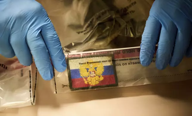 A police expert shows chevron of Russian soldier killed in the Russia-Ukraine war during the Ukrainian Interior Minister Ihor Klymenko's briefing on repatriation of fallen solders in Kyiv, Ukraine, Monday, June 23, 2025. (AP Photo/Efrem Lukatsky)