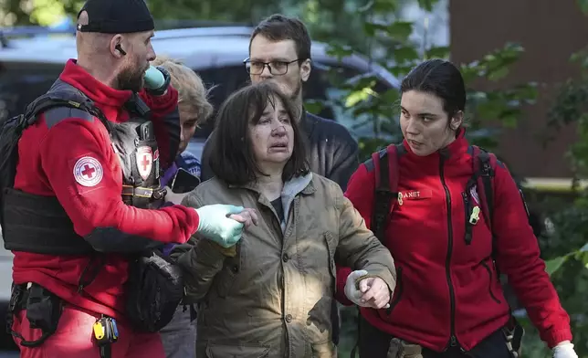 Medical workers help a woman in a yard of an apartment building destroyed after a Russian attack in Kyiv, Ukraine, early Monday, June 23, 2025. (AP Photo/Efrem Lukatsky)