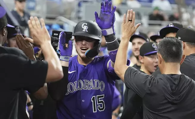 Colorado Rockies' Hunter Goodman (15) is congratulated in the dugout after hitting a solo home run during the eighth inning of a baseball game against the Miami Marlins, Tuesday, June 3, 2025, in Miami. (AP Photo/Lynne Sladky)