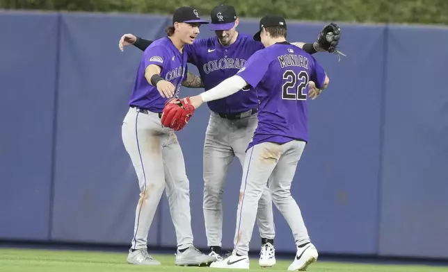 Colorado Rockies left fielder Jordan Beck, left, center fielder Brenton Doyle, center and right fielder Mickey Moniak (22) celebrate after the Rockies defeated the Miami Marlins in a baseball game, Tuesday, June 3, 2025, in Miami. (AP Photo/Lynne Sladky)