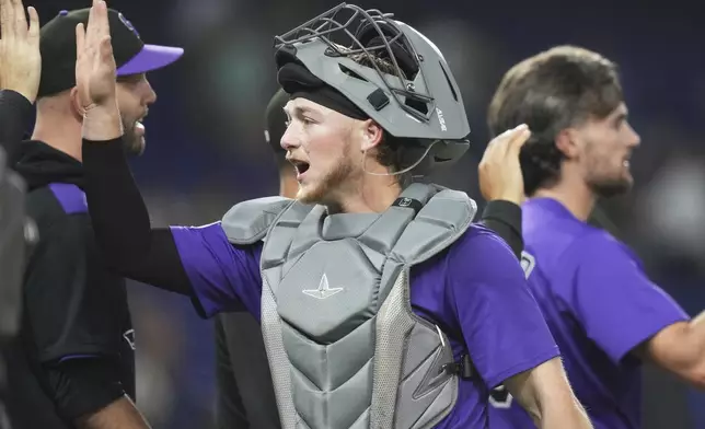Colorado Rockies catcher Hunter Goodman high-fives with his teammates after the Rockies defeated the Miami Marlins in a baseball game, Tuesday, June 3, 2025, in Miami. (AP Photo/Lynne Sladky)