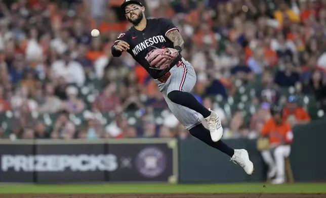Minnesota Twins shortstop Carlos Correa throws to first base after committing a fielding error during the second inning of a baseball game against the Houston Astros, Friday, June 13, 2025, in Houston. (AP Photo/Kevin M. Cox)