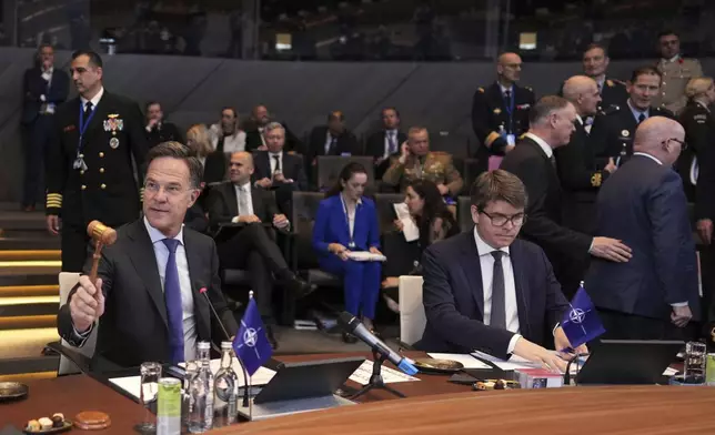 NATO Secretary General Mark Rutte, left, bangs a gavel to signify the start of a meeting of NATO defense ministers at NATO headquarters in Brussels, Thursday, June 5, 2025. (AP Photo/Virginia Mayo)