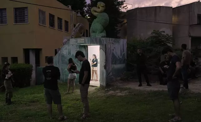 Israeli soldiers and residents gather near a public bomb shelter after receiving a message alerting about an incoming missile launched from Iran, in Holon, central Israel, on Tuesday, June 24, 2025. (AP Photo/Bernat Armangue)