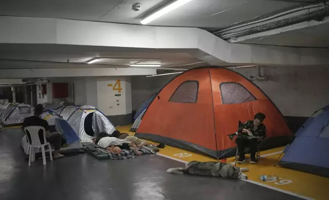 People rest and as they take shelter in an underground parking garage as a precaution against possible Iranian missile attacks, in Tel Aviv, Israel, Tuesday, June 24, 2025. (AP Photo/Ohad Zwigenberg)
