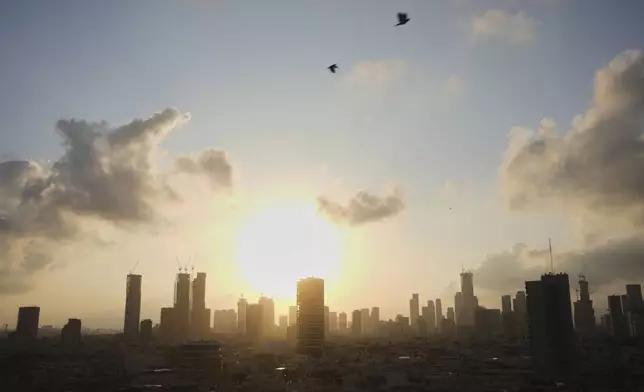 The sun raises behind city skyline just after an air raid alarm of missiles fired from Iran went off, in Tel Aviv, Israel, Tuesday, June 24, 2025. (AP Photo/Ohad Zwigenberg)