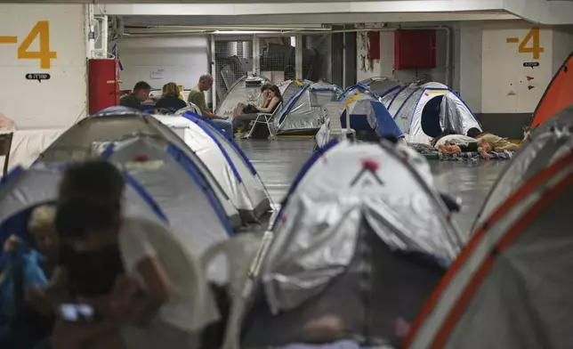 People rest and as they take shelter in an underground parking garage after an air raid alarm went off as a precaution against possible Iranian missile attacks, in Tel Aviv, Israel, Tuesday, June 24, 2025. (AP Photo/Ohad Zwigenberg)