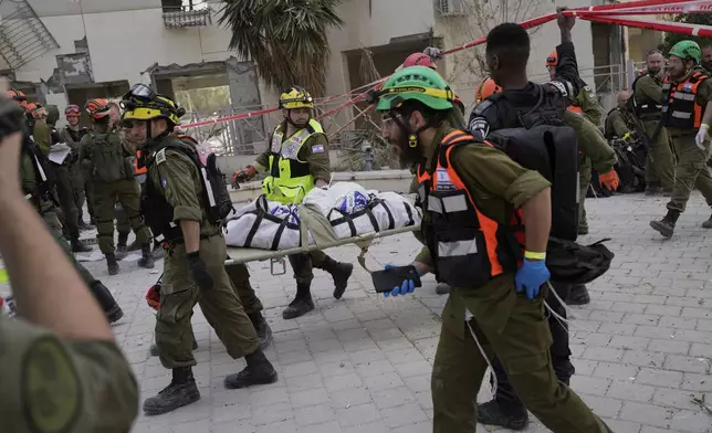 Israeli soldiers and rescue workers carry a body from a residential building destroyed by an Iranian missile strike that killed several people, in Beersheba, Israel, on Tuesday, June 24, 2025. (AP Photo/Bernat Armangue)