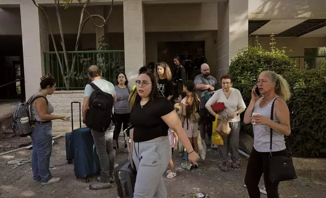 People evacuating a building next to a site stuck by an Iranian missile strike, where several people killed, in Beersheba, Israel, on Tuesday, June 24, 2025. (AP Photo/Bernat Armangue)