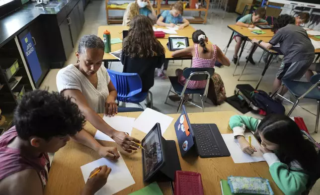 CORRECT PROGRAM NAME: Art teacher Lindsay Johnson, second from left, teaches students how to ask Canva for help during a summer class at Roosevelt Middle School, Wednesday, June 25, 2025, in River Forest, Ill. (AP Photo/Nam Y. Huh)