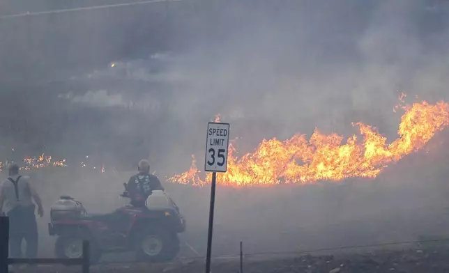 People watch as fire burns along Hatwai Road Saturday, May 31, 2025, in north Lewiston, Idaho. (August Frank/Lewiston Tribune via AP)