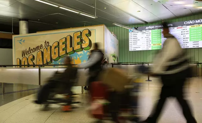 Travelers push their luggage through the international arrivals area at the Los Angeles International Airport in Los Angeles, Saturday, June 8, 2025. (AP Photo/William Liang)