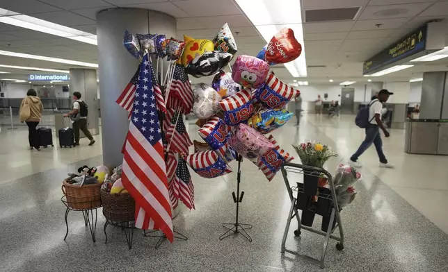 USA balloons and American flags are displayed for sale near international arrivals at Miami International Airport, Monday, June 9, 2025, in Miami. (AP Photo/Rebecca Blackwell)