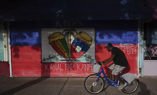 A man rides a bike past shops in Miami's Little Haiti neighborhood, Friday, June 6, 2025. (AP Photo/Rebecca Blackwell)