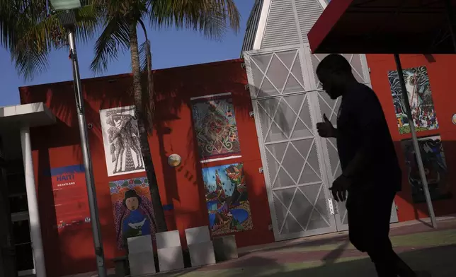 Haitian art is displayed on a wall as a man practices dance moves for a father-daughter performance organized by the Miami Police Athletic League, outside the Little Haiti Cultural Complex in Miami, Friday, June 6, 2025. (AP Photo/Rebecca Blackwell)