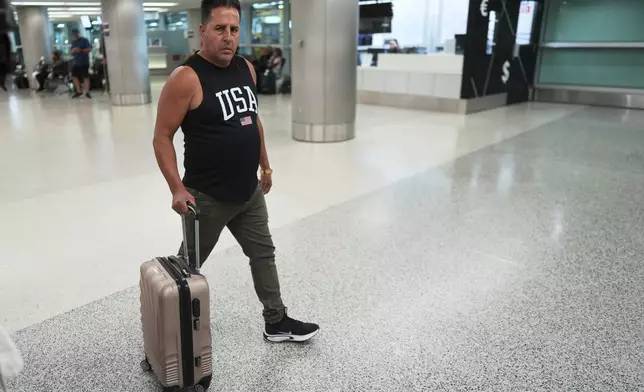 A man arriving from Cuba wears a USA tee-shirt, as he walks out of international arrivals at Miami International Airport, Monday, June 9, 2025, in Miami. (AP Photo/Rebecca Blackwell)