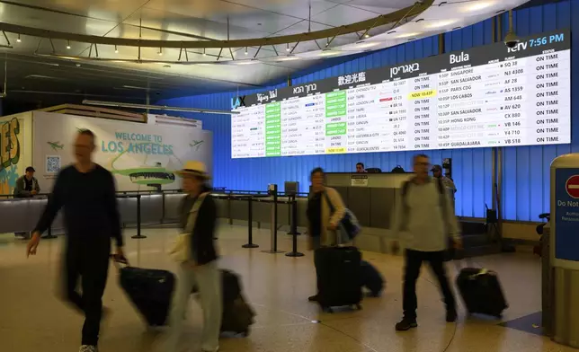 Travelers cart their luggage through the international arrivals area at the Los Angeles International Airport in Los Angeles, Saturday, June 8, 2025. (AP Photo/William Liang)