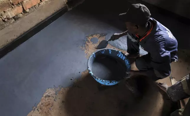 Alex Wanda, a construction officer at EarthEnable, installs paste on floors May 17, 2025, in Jinja, Uganda. (AP Photo/Hajarah Nalwadda)