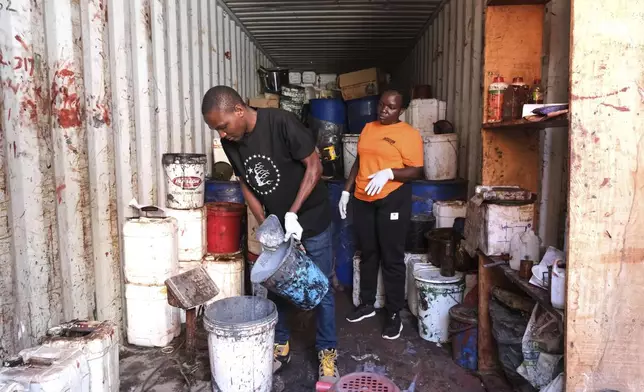 Alfred Benja, left, operations officer, mixes floor paste as Noeline Mutesi, sales and marketing manager, looks on while in the workshop at EarthEnable, where they make a clay-based earthen floor on May 17, 2025, in Jinja, Uganda. (AP Photo/Hajarah Nalwadda)