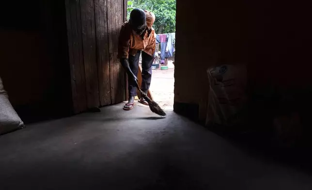 Simon Tigawalana sweeps his house with a clay-based earthen floor by EarthEnable on May 16, 2025, in Jinja, Uganda. (AP Photo/Hajarah Nalwadda)