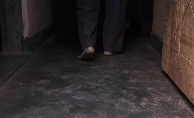 Simon Tigawalana walks into his house with some clay-based earthen floors by EarthEnable on May 16, 2025, in Jinja, Uganda. (AP Photo/Hajarah Nalwadda)