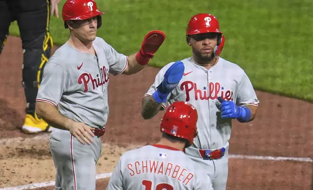 Philadelphia Phillies' Edmundo Sosa, right, and J.T. Realmuto, left, score on a single by Trea Turner off Pittsburgh Pirates pitcher Chase Shugart during the fourth inning of a baseball game in Pittsburgh, Friday, June 6, 2025. (AP Photo/Gene J. Puskar)