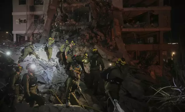 Israeli security forces inspect destroyed buildings that were hit by a missile fired from Iran, near Tel Aviv, Israel, Sunday, June 15, 2025. (AP Photo/Ohad Zwigenberg)