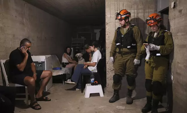 Israeli residents and security forces stay in a shelter of a residential area that was hit by a missile fired from Iran, in the central Israeli city of Bat Yam, early Sunday, June 15, 2025. (AP Photo/Ohad Zwigenberg)