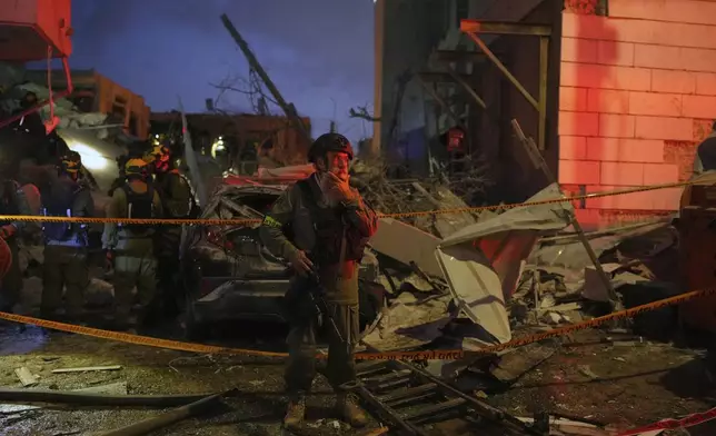 Israeli security forces inspect destroyed buildings that were hit by a missile fired from Iran, near Tel Aviv, Israel, Sunday, June 15, 2025. (AP Photo/Ohad Zwigenberg)