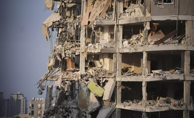 Israeli security forces inspect a destroyed building that was hit by a missile fired from Iran, near Tel Aviv, Israel, Sunday, June 15, 2025. (AP Photo/Ohad Zwigenberg)