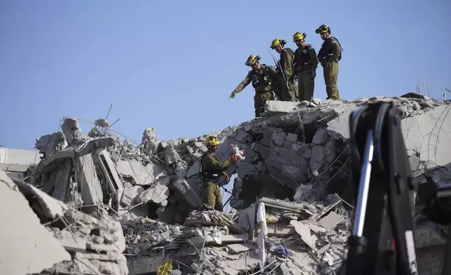 Israeli security forces inspect destroyed houses that were struck by a missile fired from Iran, in Rishon Lezion, Israel on Saturday, June 14, 2025. (AP Photo/Ohad Zwigenberg)