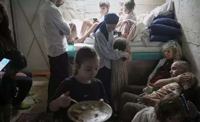 Israelis take shelter in a basement as a siren sounds a warning following missile launches from Iran, in Jerusalem, Sunday, June 15, 2025. (AP Photo/Ohad Zwigenberg)
