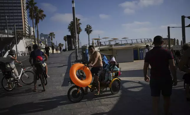 People walk along the beachfront promenade in Tel Aviv, Israel, on Saturday, June 14, 2025. (AP Photo/Ohad Zwigenberg)