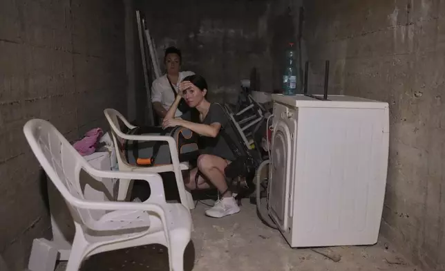Israeli locals stay in a shelter of a residential area that was hit by a missile fired from Iran, near Tel Aviv, Israel, early Sunday, June 15, 2025. (AP Photo/Ohad Zwigenberg)