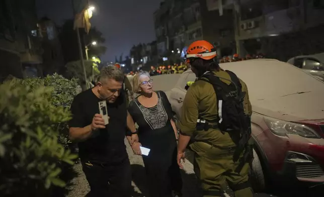 Israeli locals leave a residential area that was hit by a missile fired from Iran, near Tel Aviv, Israel, early Sunday, June 15, 2025. (AP Photo/Ohad Zwigenberg)