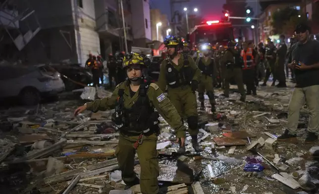 Israeli security forces inspect destroyed buildings that were hit by a missile fired from Iran, near Tel Aviv, Israel, Sunday, June 15, 2025. (AP Photo/Ohad Zwigenberg)
