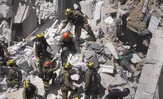 Israeli soldiers dig through rubble to search for survivors in a residential area hit by a missile fired from Iran, in Bat Yam, central Israel, Sunday, June 15, 2025.(AP Photo/Ariel Schalit)