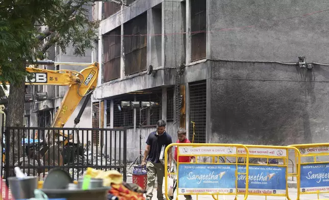 A man carries luggage as he comes out from Thursday's Air India plane crash site in Ahmedabad, India, Sunday, June 15, 2025. (AP Photo/Ajit Solanki)