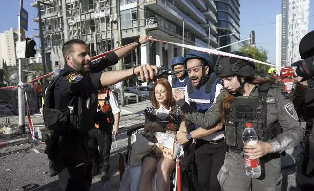 A woman is evacuated from the site of a direct hit from an Iranian missile strike in Ramat Gan, Israel, Thursday, June 19, 2025. (AP Photo/Oded Balilty)