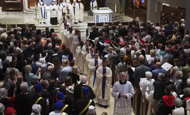 Twelve newly ordained priests walk past pews of family, friends and community members, after their ordination Mass at the Cathedral of Saint Thomas More in Arlington, Va., on Saturday, June 7, 2025. (AP Photo/Jessie Wardarski)