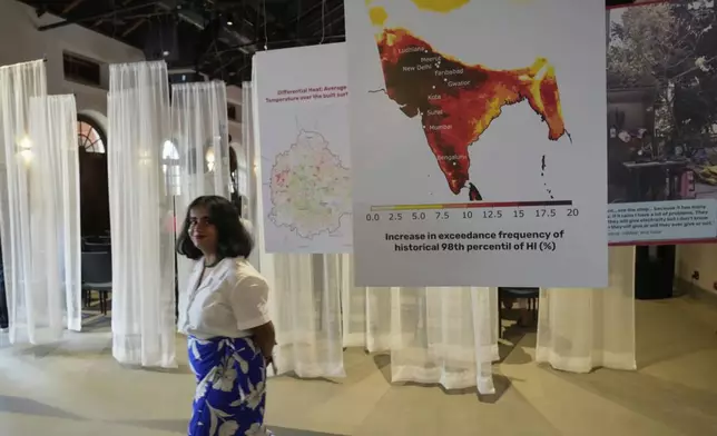 A woman walks past interpretive panels highlighting the impact of heat at the Sweat and Concrete 2025 event in Bengaluru, India, Thursday, May 29, 2025. (AP Photo/Aijaz Rahi)