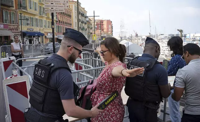 A police officer checks a woman ahead of the UN Ocean Conference, Saturday, June 7, 2025 in Nice, French Riviera. (AP Photo/Laurent Cipriani)