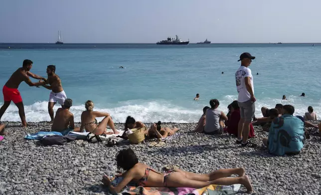 People enjoy the beach as vessels sail during the "Ocean Wonders" event in honor of World Oceans Day ahead of the U.N. Ocean Conference on Sunday, June 8, 2025, in Nice, France. (AP Photo/Annika Hammerschlag)