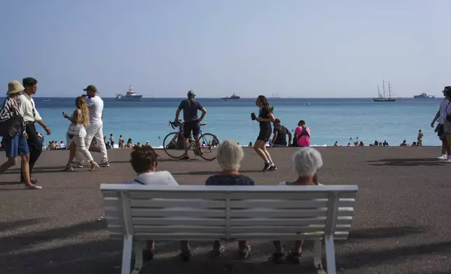 People enjoy the beach as vessels sail during the "Ocean Wonders" event in honor of World Oceans Day ahead of the U.N. Ocean Conference on Sunday, June 8, 2025, in Nice, France. (AP Photo/Annika Hammerschlag)