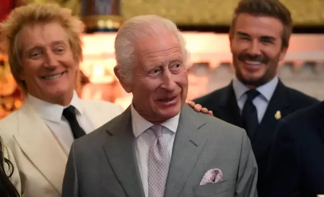 FILE - King Charles III smiles as he attends the inaugural King's Foundation charity awards at St James's Palace in London, Tuesday, June 11, 2024, with British pop icon Rod Stewart, left, and former footballer David Beckham in the background. (AP Photo/Kirsty Wigglesworth,Pool, File)