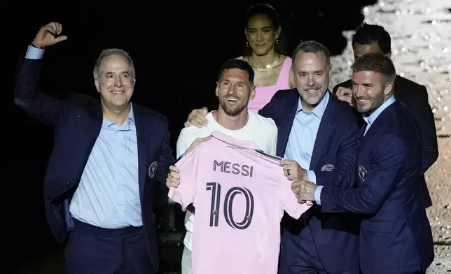 FILE _ lnInternational superstar Lionel Messi, center left, holds his new Inter Miami team jersey as he poses with team co-owners Jorge Mas, left, Jose Mas, second right, and David Beckham, right, at an event to present him to fans one day after his signing, Sunday, July 16, 2023, in Fort Lauderdale, Fla. (AP Photo/Rebecca Blackwell, File)