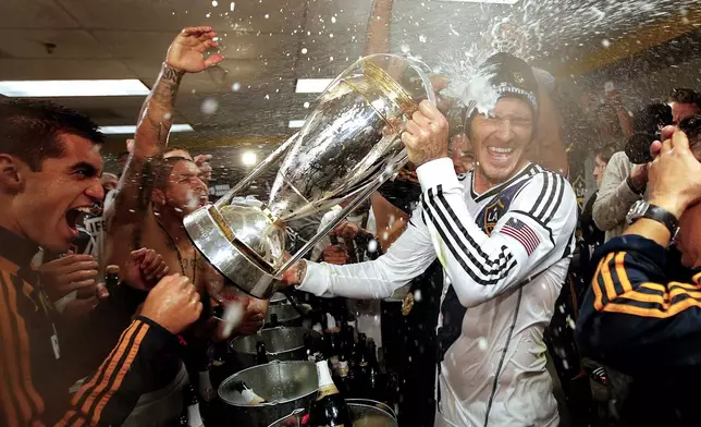 FILE - Los Angeles Galaxy's David Beckham, center, is sprayed with champagne as they celebrate in the dressing room after defeating the Houston Dynamo 3-1 in the MLS Cup championship soccer game in Carson, Calif., Dec. 1, 2012. (AP Photo/Jae C. Hong, File)