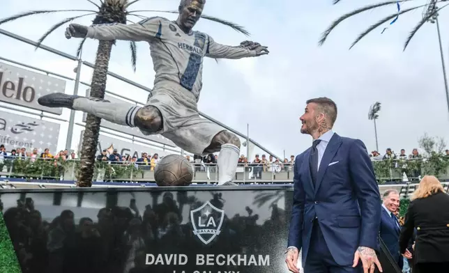 FILE - Former LA Galaxy MLS soccer midfielder David Beckham looks at a statue of himself at Legends Plaza in front of Dignity Health Sports Park in Carson, Calif., Saturday, March 2, 2019. (AP Photo/Ringo H.W. Chiu, File)