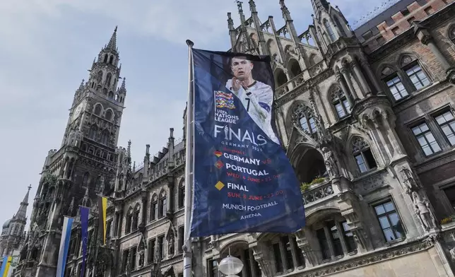 A flag with Ronaldo of Portugal waves in front of the town hall in Munich, Germany, ahead of the Nations League Finals, starting tomorrow with Germany against Portugal, Tuesday, June 3, 2025. (AP Photo/Martin Meissner)
